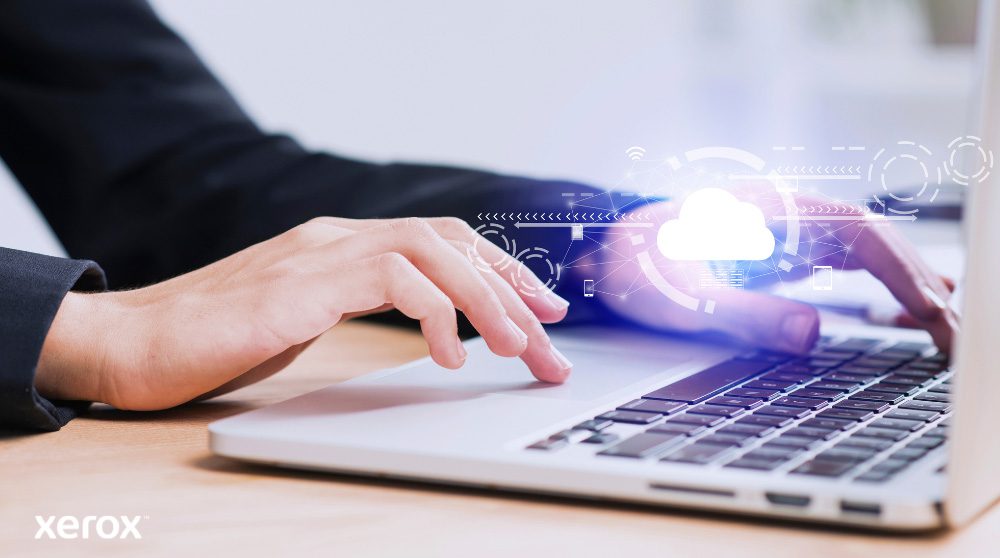 A person's hands are shown typing on a laptop keyboard, with a glowing cloud icon and network connections superimposed over the image, symbolizing cloud connectivity and digital workflows.